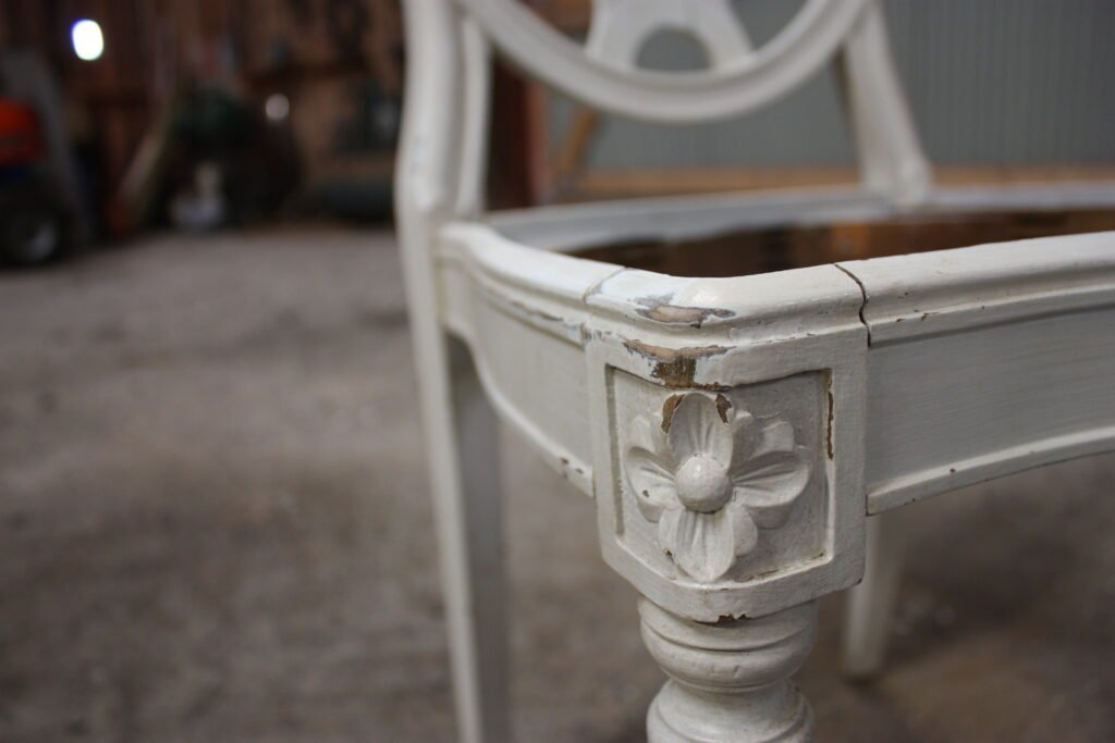 Detalj av en vitmålad stol under renovering